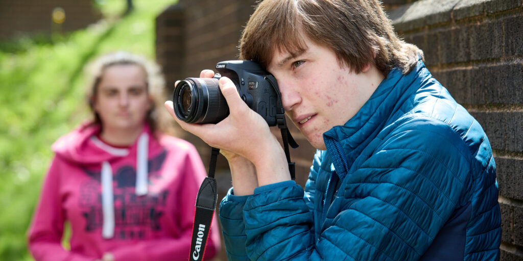 Photo of a photography student using a camera outdoors