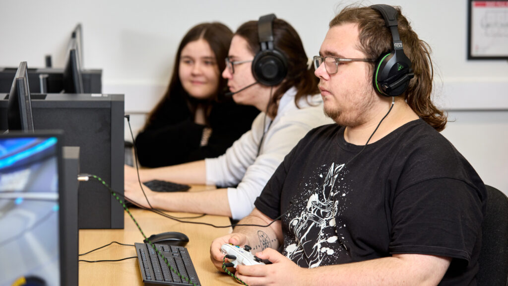 Photo of students wearing headphones and using a games consoles