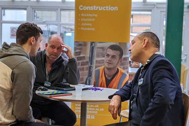 A visitor talking to tutors at the What's Next apprenticeship information event.