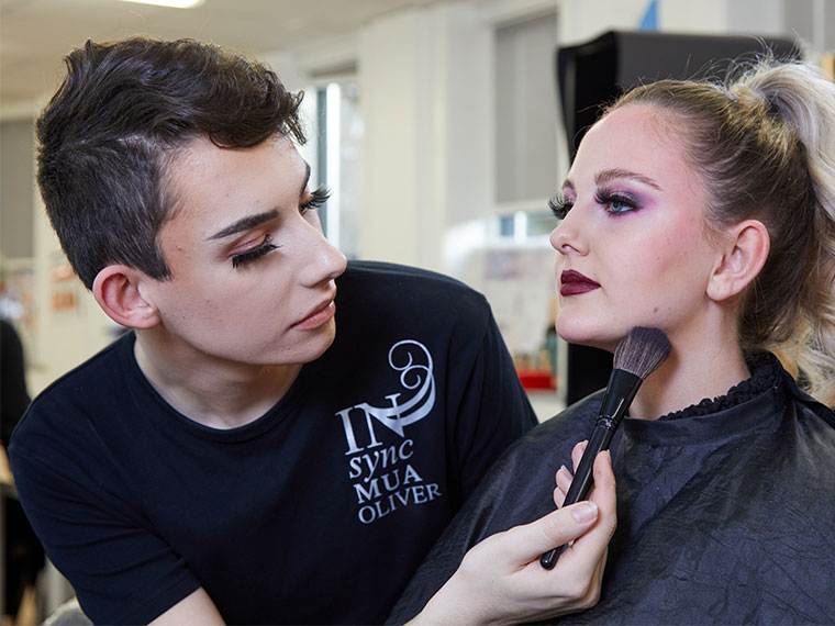 Oliver Helm applying make-up to a model.
