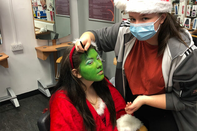 Level 2 Hairdressing student Amy Whiteley creating a look on a model which is inspired by the Grinch.