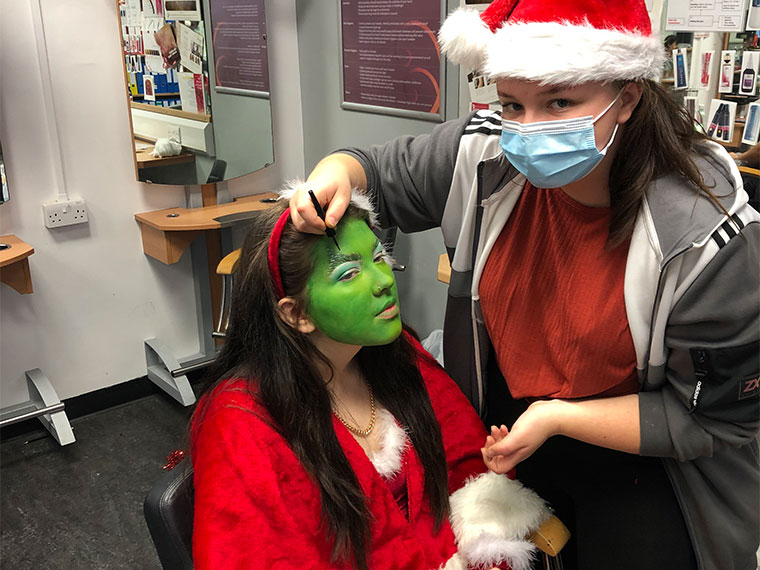 Level 2 Hairdressing student Amy Whiteley creating a look on a model which is inspired by the Grinch.