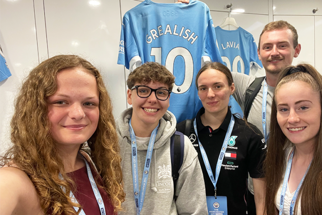 Our Sport students in the football museum with tutor Callum Lister holding a Jack Grealish Shirt.