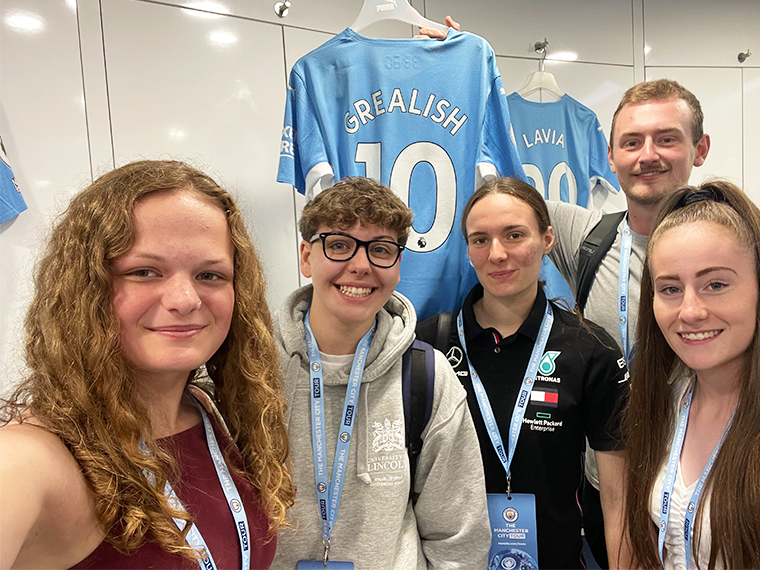 Our Sport students in the football museum with tutor Callum Lister holding a Jack Grealish Shirt.