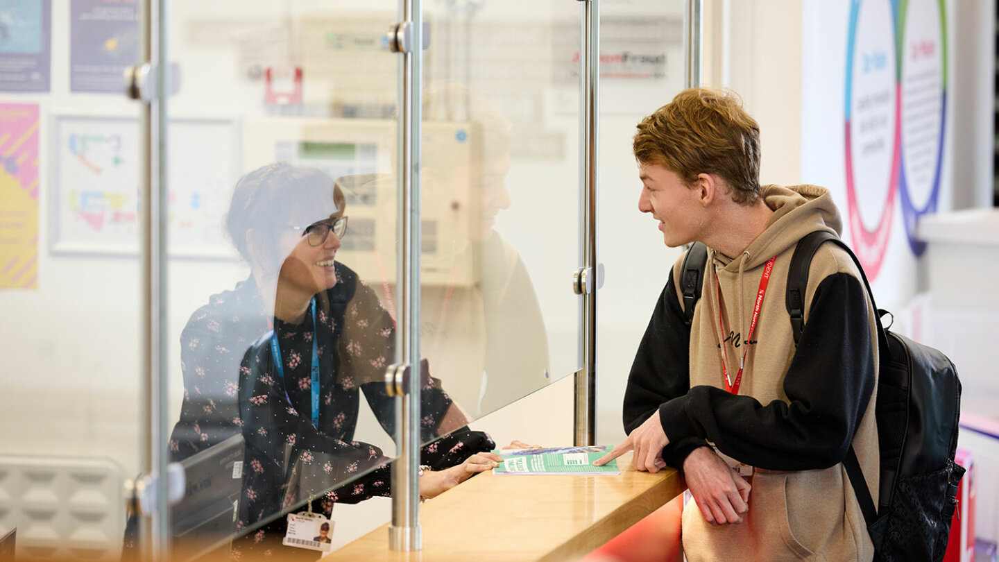 A student talking to a member of staff at the reception